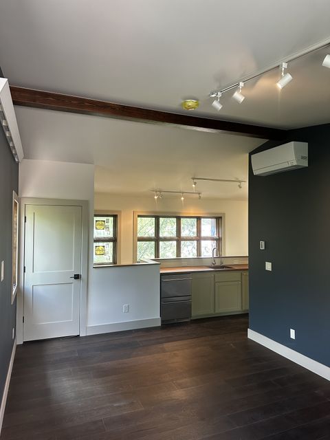 Open living area with exposed beam and kitchen beyond