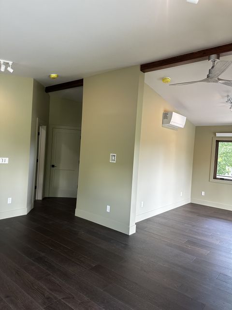 Open floor plan with wood beam and dark floors
