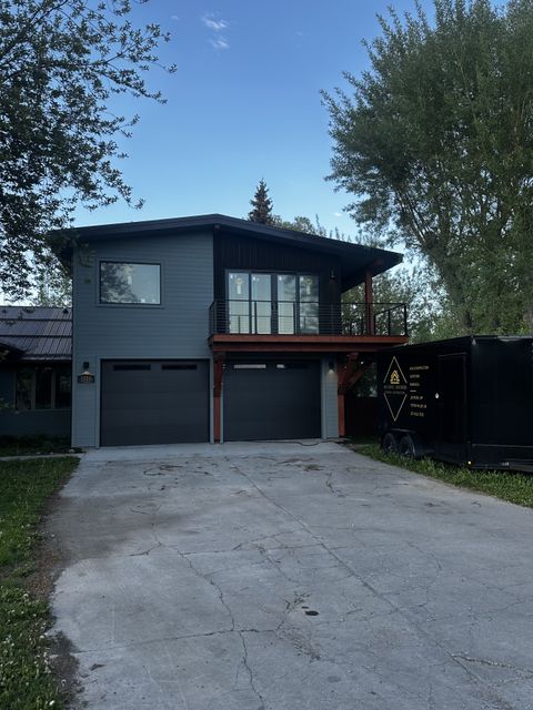 Two-story garage apartment with dark siding and a long driveway