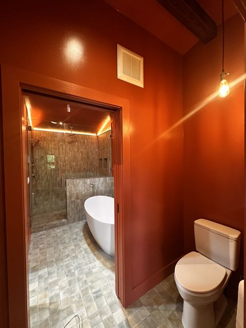 Bathroom with rust-red walls and a freestanding tub