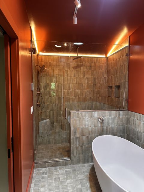 Tiled walk-in shower and freestanding tub with warm accent lighting