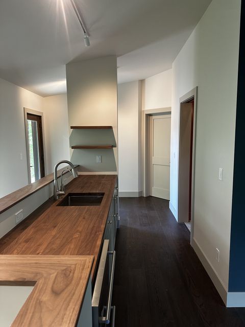 Galley kitchen with butcher-block counters and dark wood floors