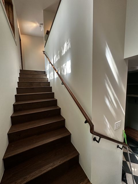 Wood staircase with a wall-mounted handrail in a bright stairwell